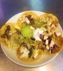 Five small tacos with grilled meat, vegetables, guacamole, and sour cream.