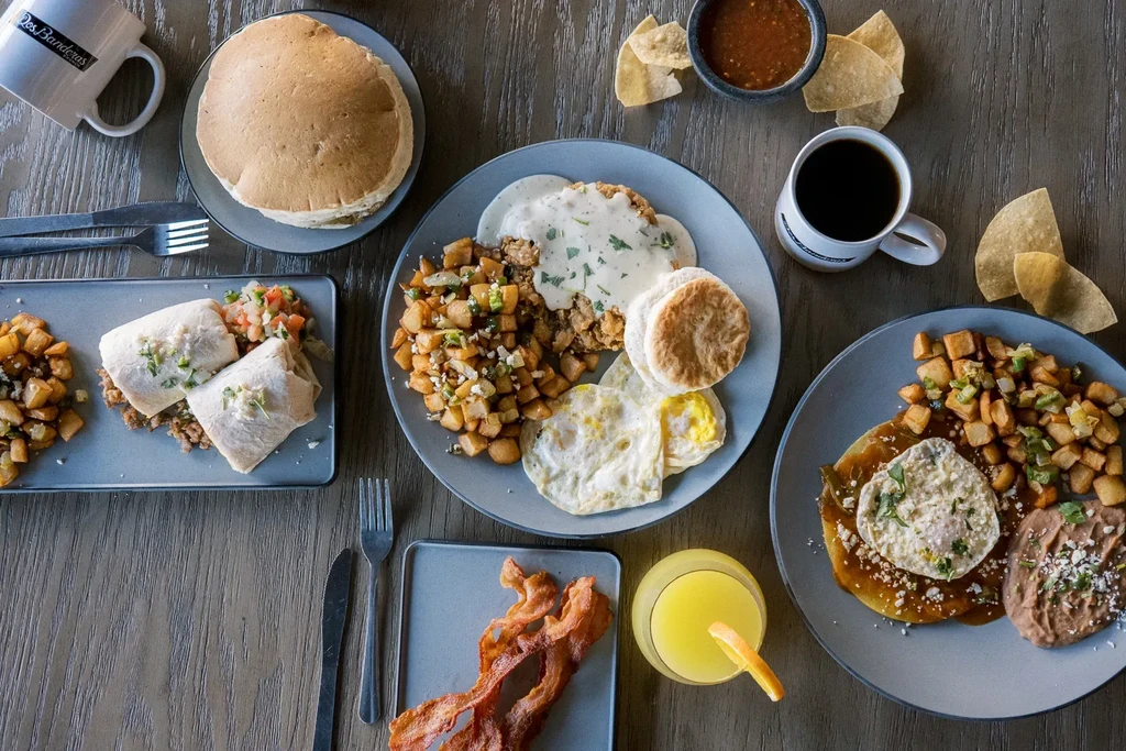 Overhead view: various breakfast and brunch dishes and drinks on a wooden table.