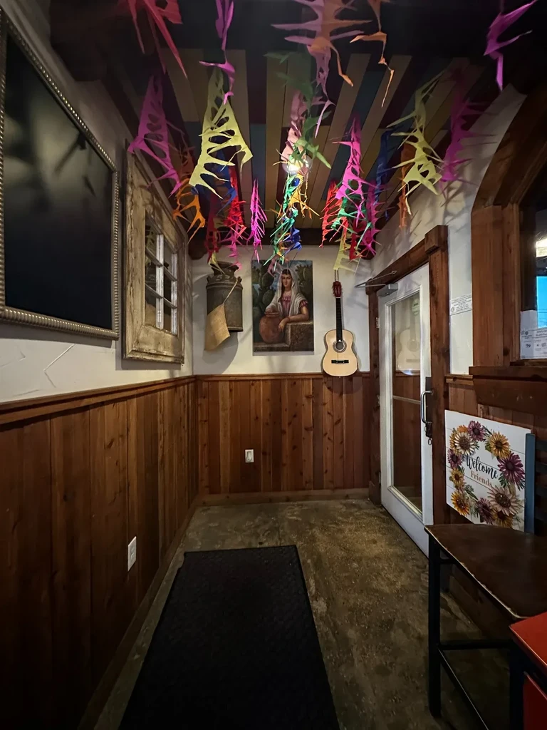 Restaurant entrance with vibrant paper ceiling decor and wood-paneled walls.