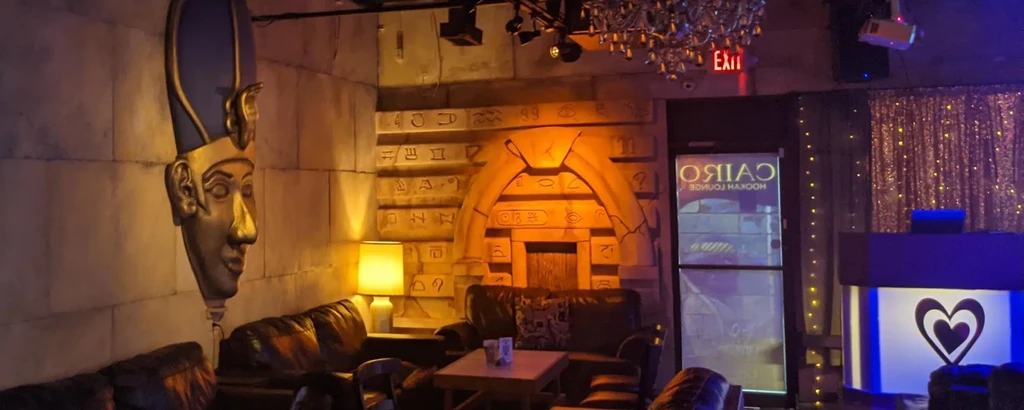 Dimly lit Cairo Hookah Lounge with Egyptian-themed walls and seating.