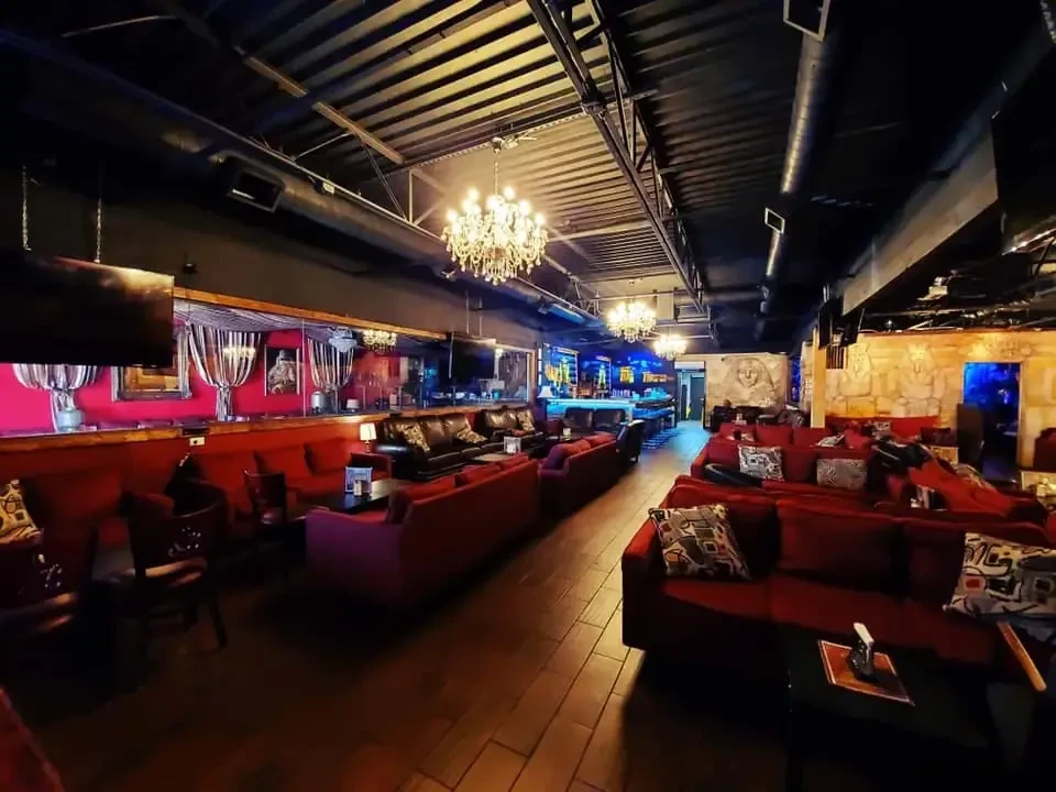 Luxurious, exotic lounge with red sofas, ornate decor, and dim lighting.