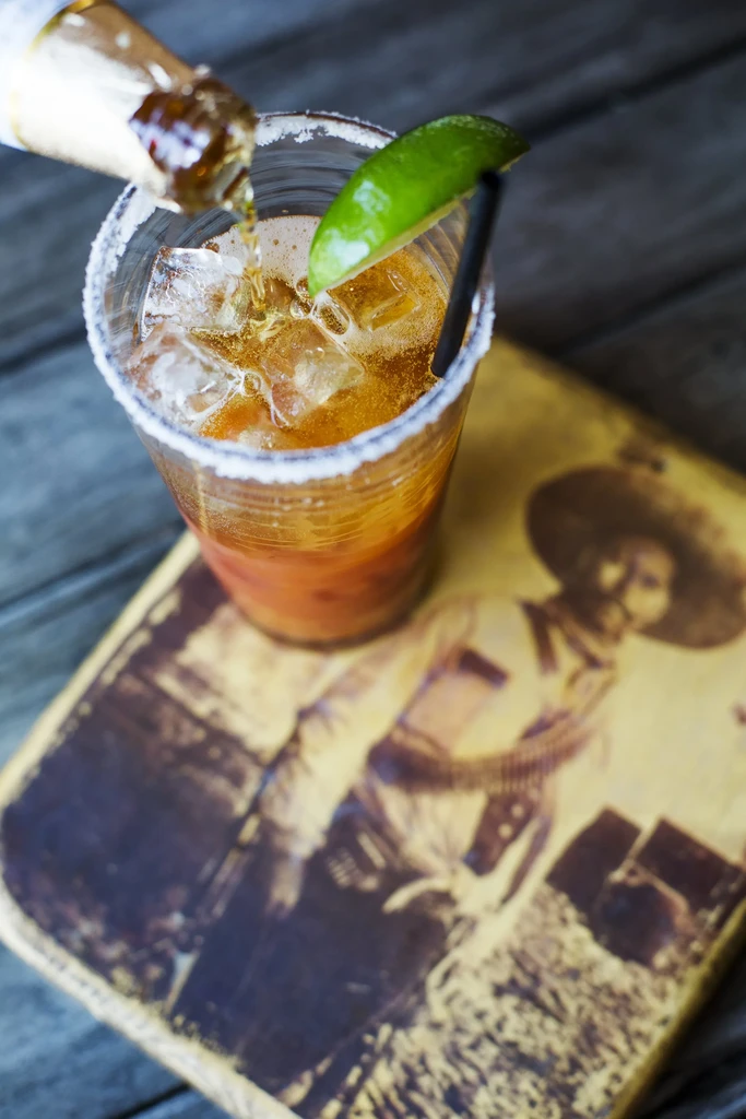 Overhead: Beer poured into salted glass with ice, lime, straw.