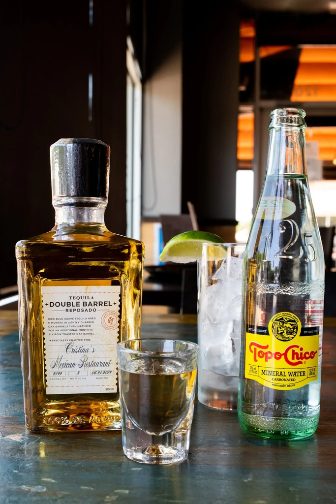 Cristina's Tequila bottle, shot, Topo Chico, and ice glass.