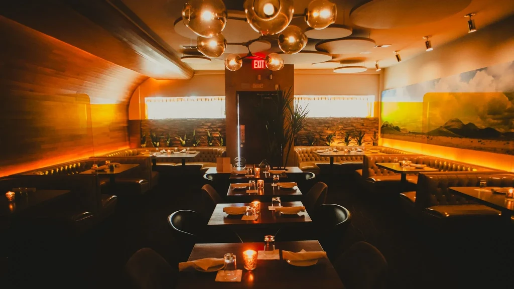Warmly lit, empty restaurant interior with booths and a desert mural.