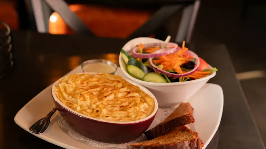 Casserole with golden mashed potatoes, fresh salad, bread, and dressing.