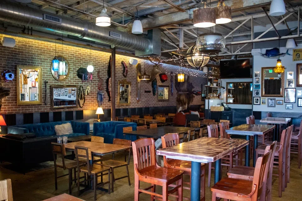 Eclectic, rustic industrial bar interior with brick walls and velvet couches.