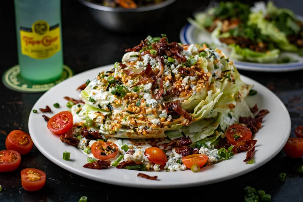 Wedge salad with creamy dressing, blue cheese, bacon, nuts, and tomatoes.