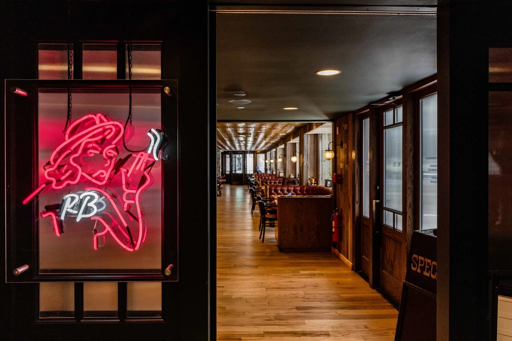 Restaurant entrance with red neon sign, dark wood, and red booths.
