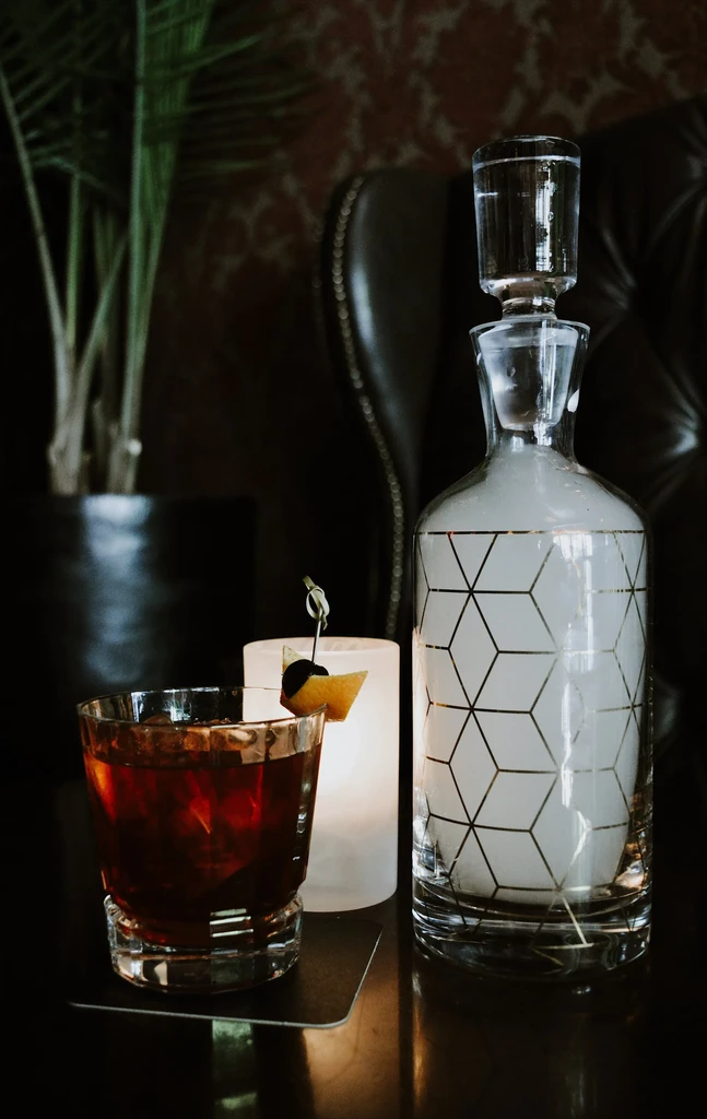 Elegant cocktail, smoky decanter, and glowing light in a luxury setting.