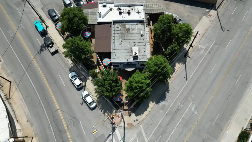 Aerial view of a triangular building with colorful umbrellas at an intersection.