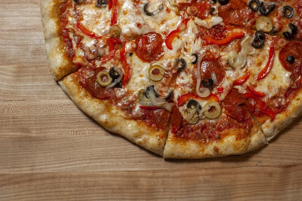 Overhead close-up of pizza with pepperoni, cheese, olives, peppers, and onions.