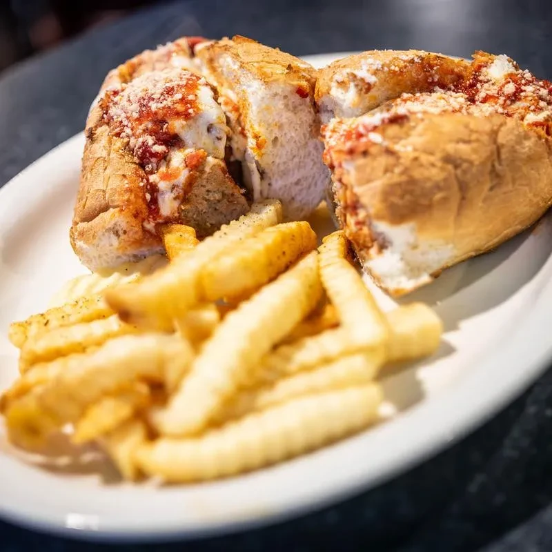 A sliced meatball or chicken parmesan sub with crinkle-cut fries.