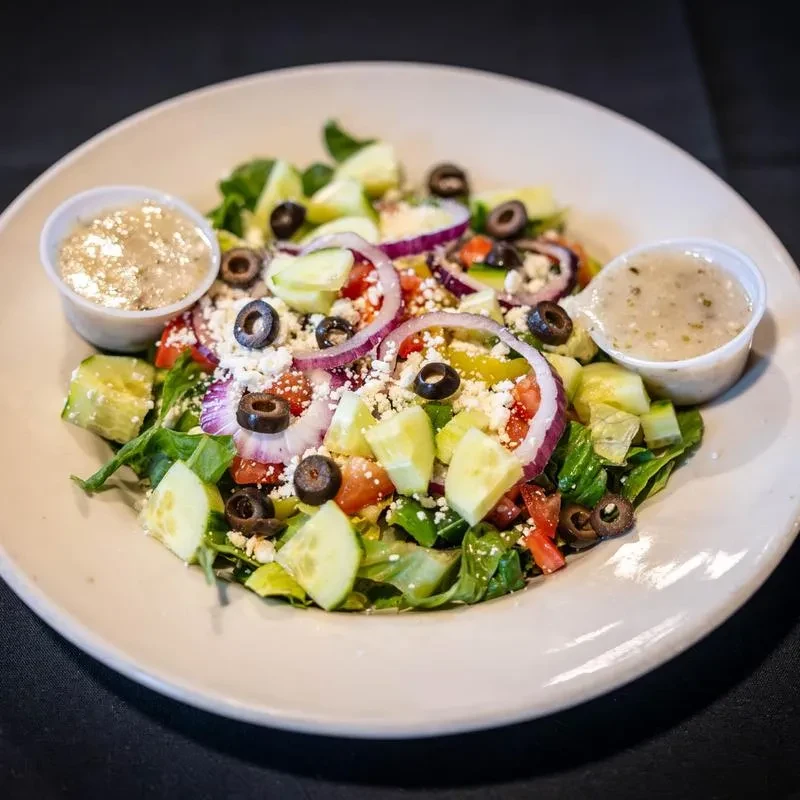 Greek salad with lettuce, tomatoes, cucumber, feta, olives, and vinaigrette.