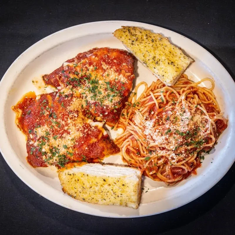 Top-down view of chicken parmesan, spaghetti, and garlic bread.