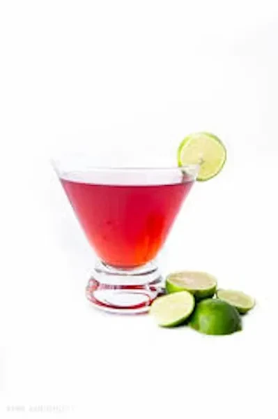Reddish-pink cocktail in martini glass with lime slice and cut limes.