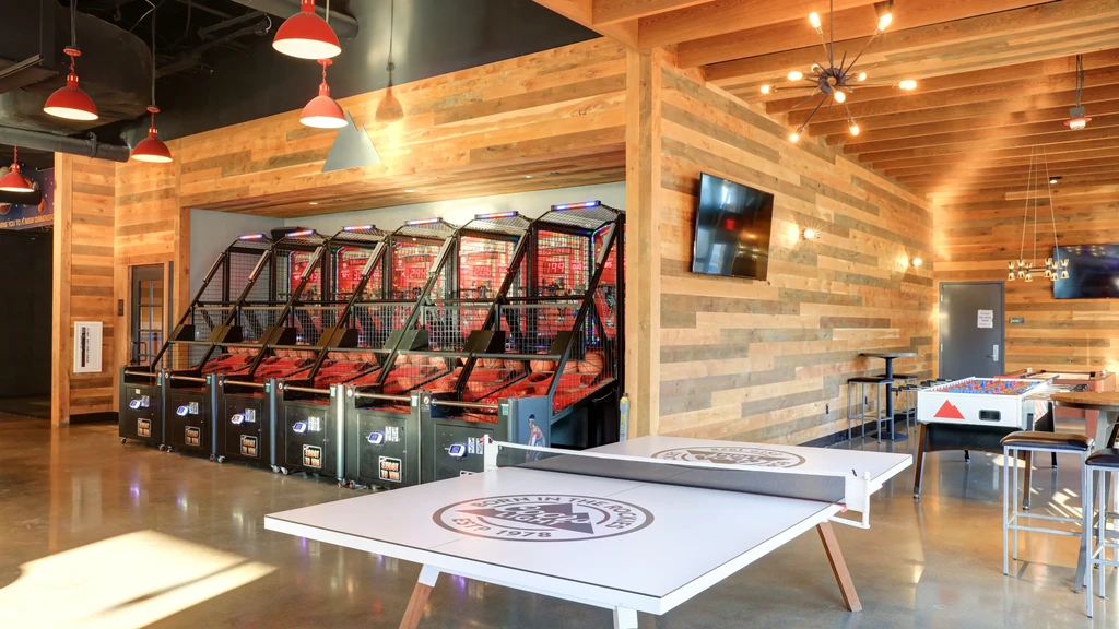 Modern entertainment venue with arcade games, ping-pong, and foosball tables.