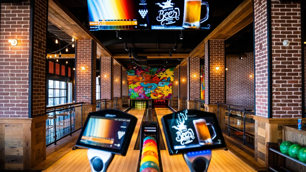 Modern bowling alley with two lanes, digital screens, and a graffiti mural.