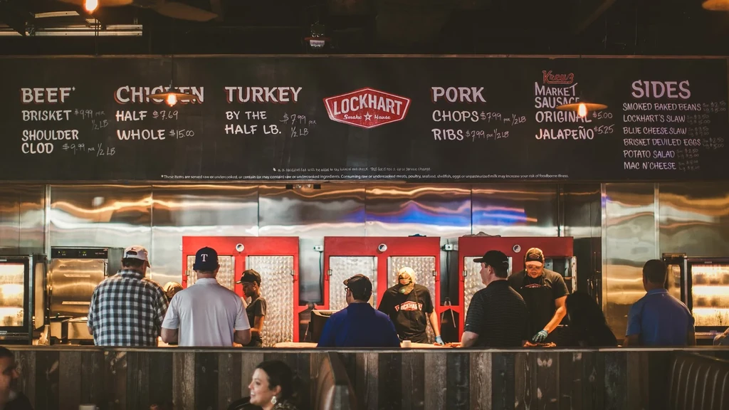 Lockhart Smoke House service counter with menu board, customers, and employees.