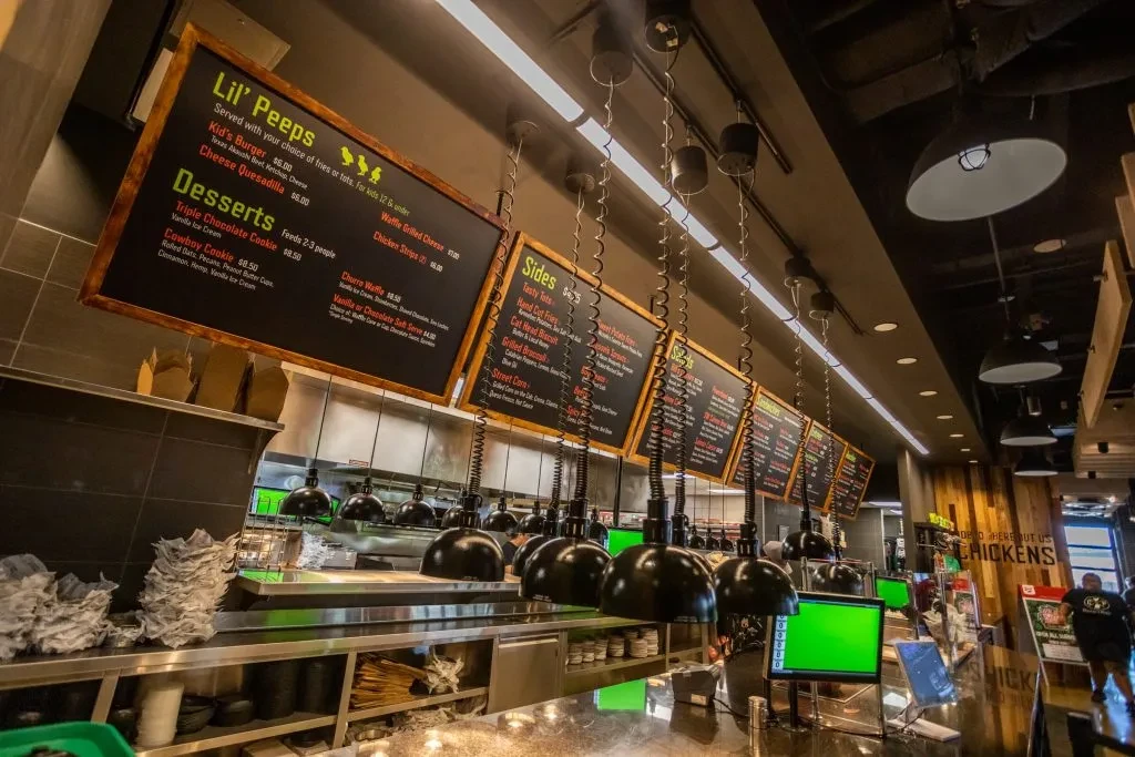 Modern restaurant interior: menu boards, stainless counter, and digital screens.