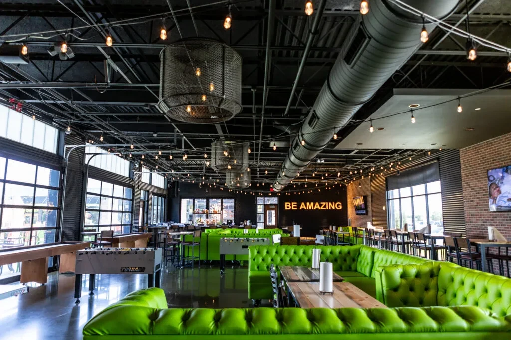 Vibrant industrial restaurant interior with lime green booths and games.