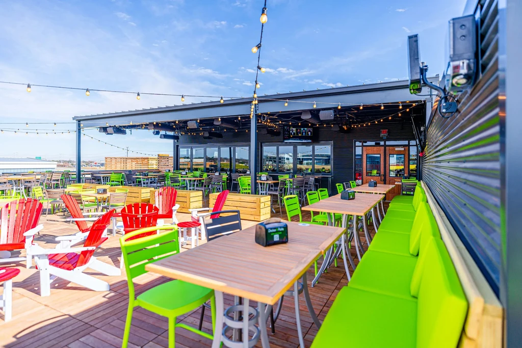 Colorful, empty restaurant patio with varied seating and string lights.