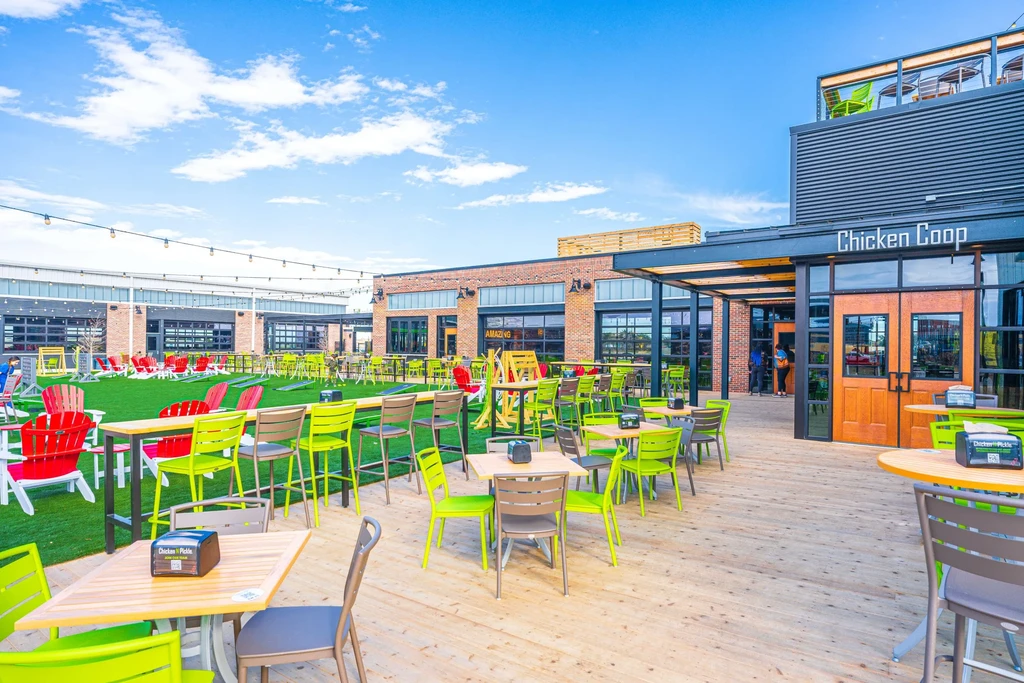 Vibrant outdoor restaurant with patio, turf games, and brick buildings.