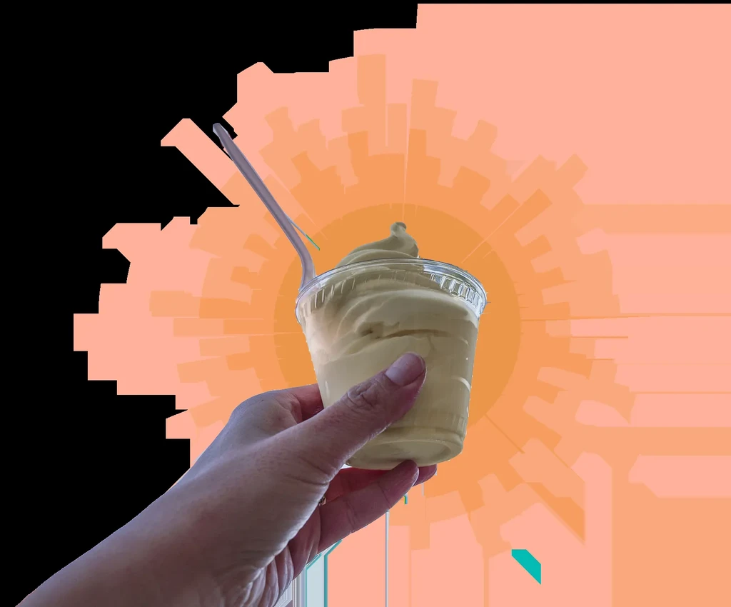 Hand holding yellow soft-serve in cup with spoon, abstract radial background.
