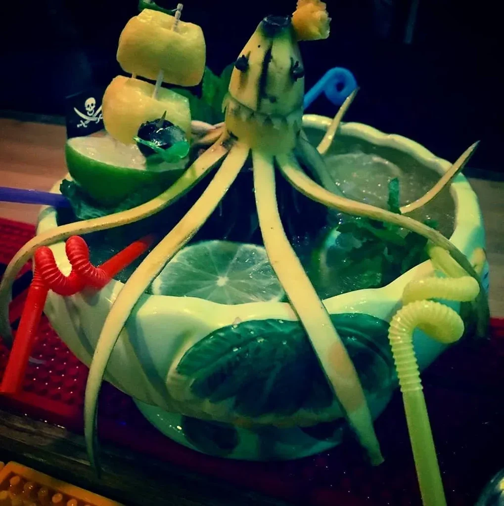 Elaborate tiki punch bowl with banana octopus, citrus ship, and straws.