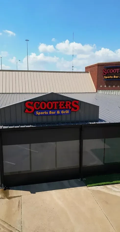 SCOOTERS Sports Bar & Grill, red sign on corrugated facade, blue sky.