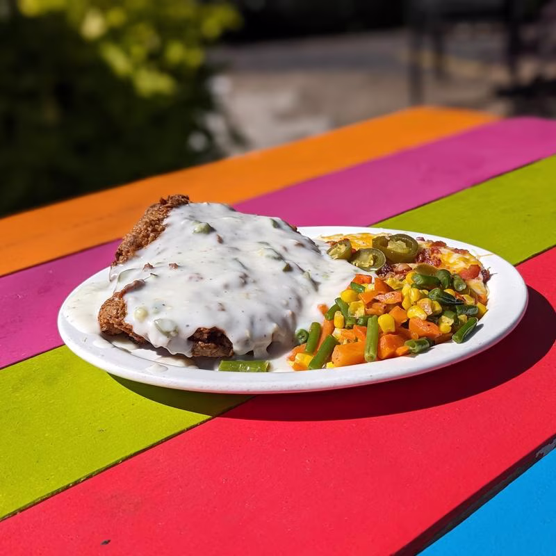 Fried cutlet with gravy, mixed vegetables, and a jalapeño side.