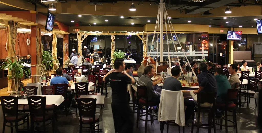 Rustic nautical-themed restaurant interior bustling with diners and a ship's mast.