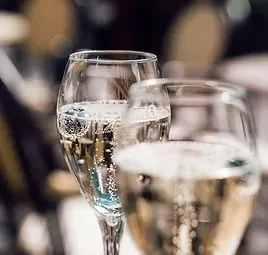 Two effervescent champagne flutes, one in sharp focus, against blurred background.