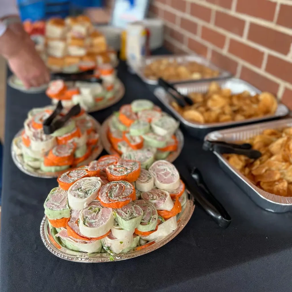 Buffet table with pinwheel wraps, sandwiches, and chips.