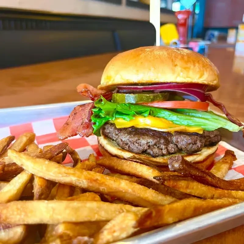 Generously stacked burger with bacon, cheese, and golden fries.