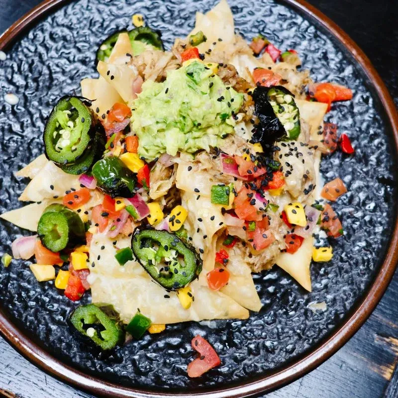Vibrant gourmet nachos with guacamole, shredded meat, and charred jalapeños.