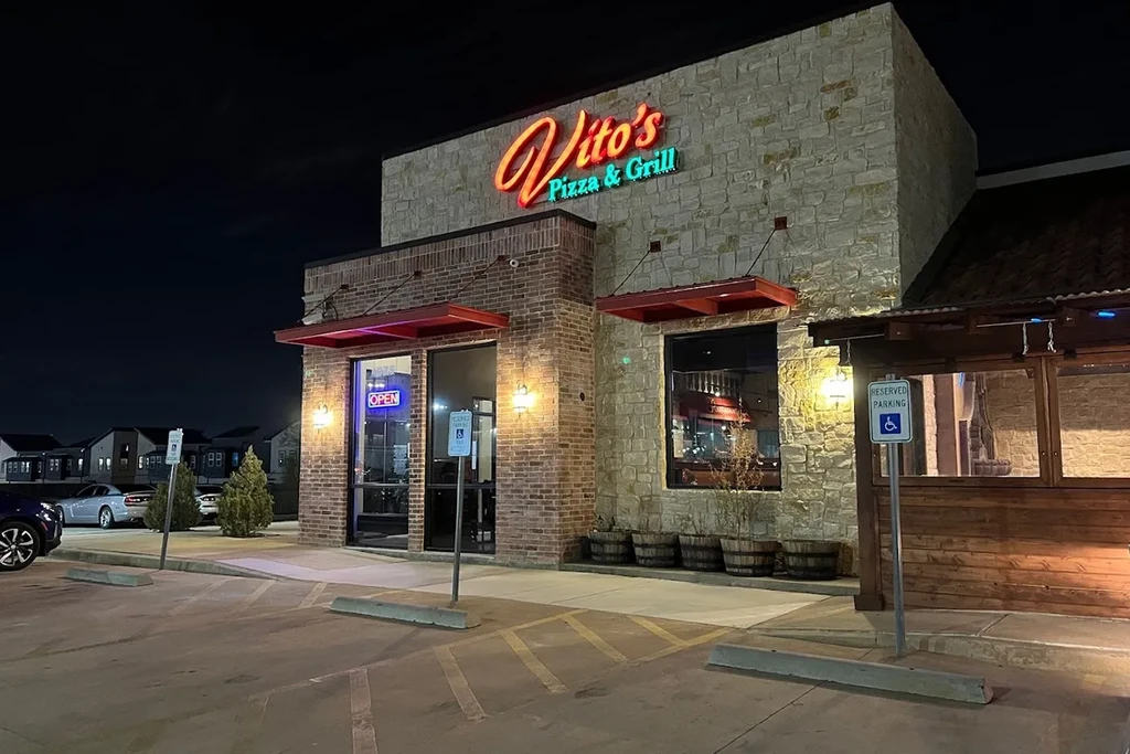Vito's Pizza & Grill restaurant exterior at night with glowing neon signs.