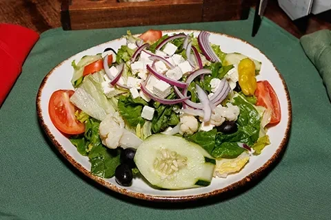 Vibrant salad with feta, olives, and fresh vegetables in a white bowl.