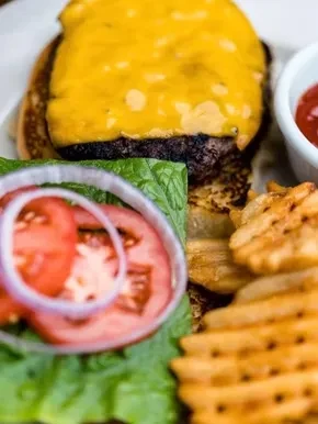 Open-faced cheesy burger, lettuce, tomato, waffle fries, and ketchup.