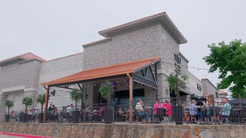 Exterior of LULU restaurant: modern gray building with a lively patio.