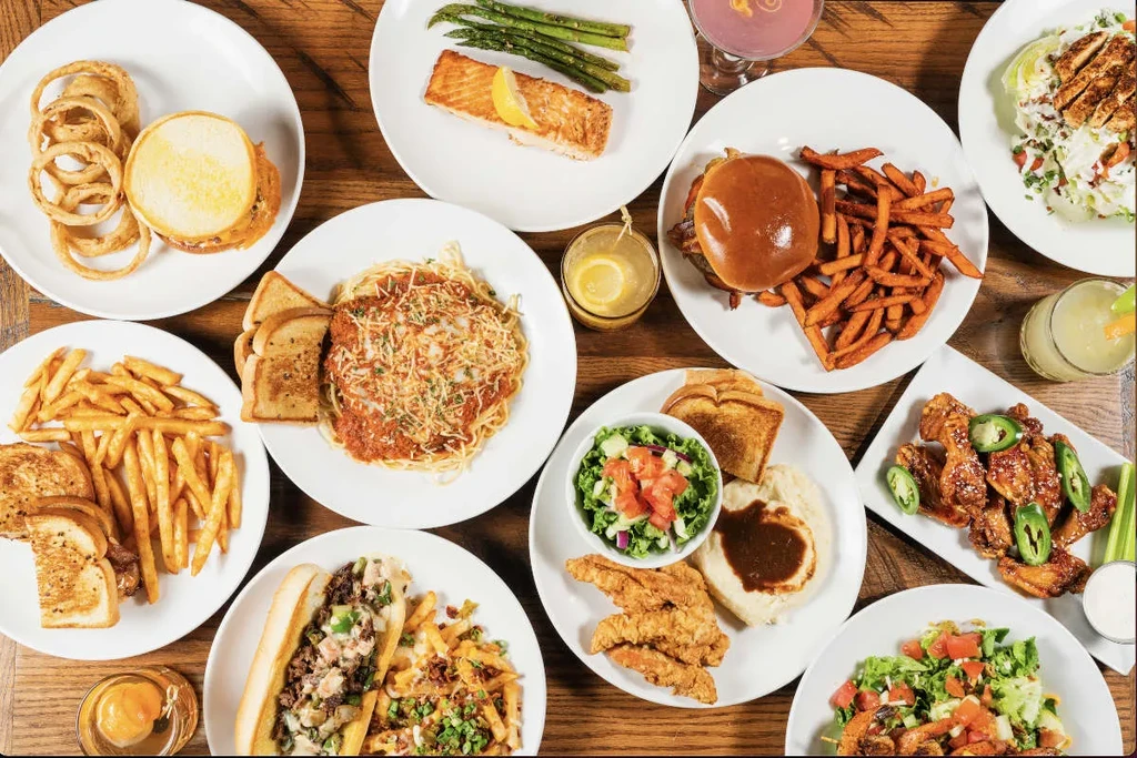Overhead shot of diverse food dishes and drinks on a rustic wooden table.