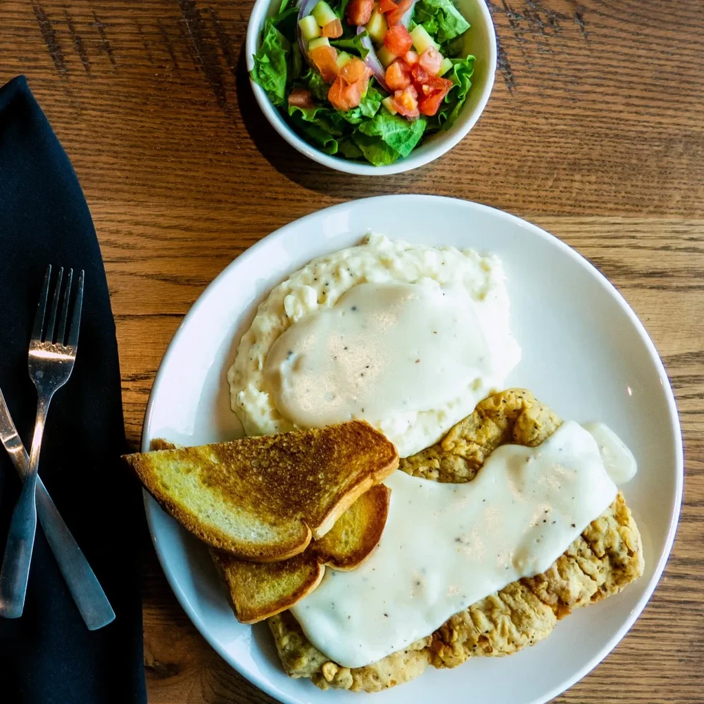 Overhead view of a country fried steak meal with mashed potatoes and salad.