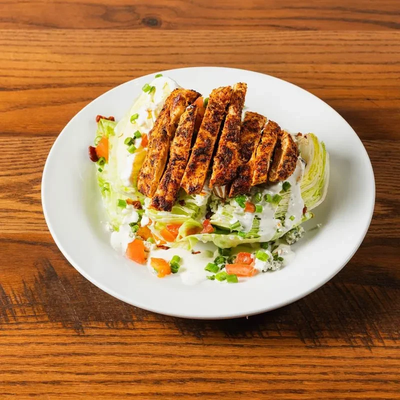 Grilled chicken wedge salad with blue cheese, bacon, and tomato.