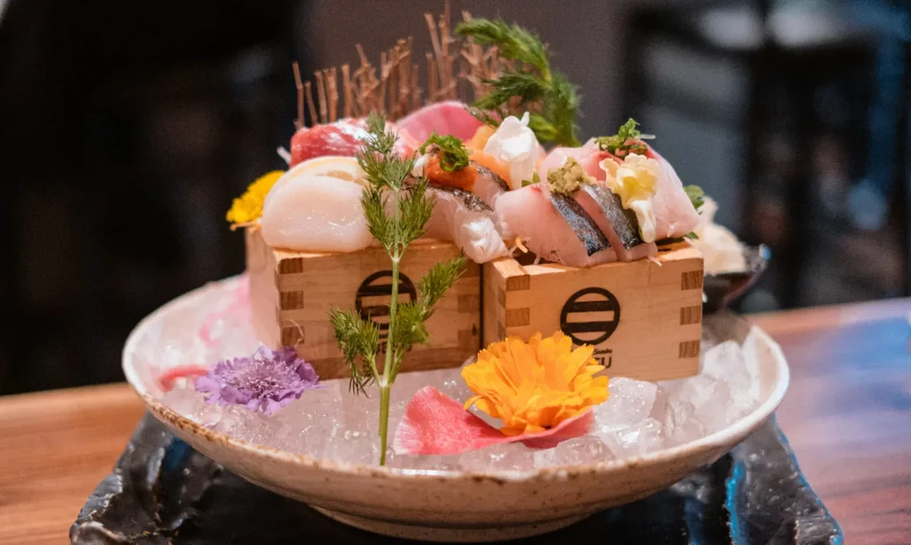 Sashimi with tuna, scallop, white fish, flowers, on ice.