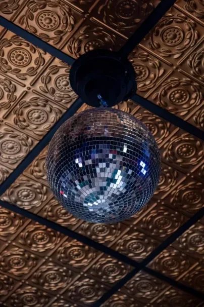 Mirrored disco ball hangs from an ornate gold embossed tin ceiling.