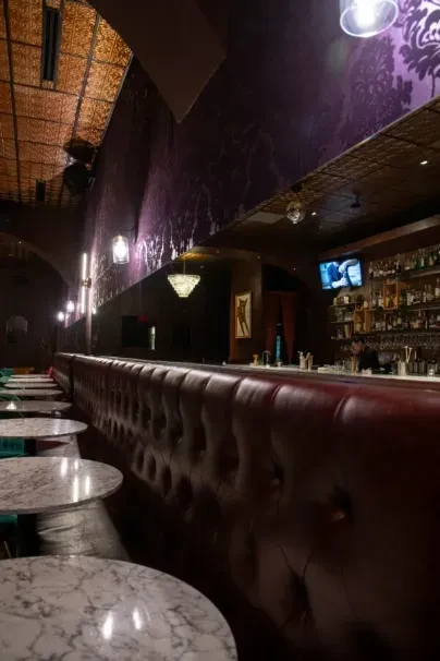 Tufted red leather booths, marble tables, and a dim, upscale bar.