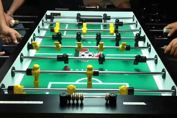 Foosball game in progress, showing hands, ball, and Tornado table.