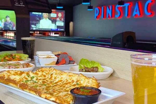 Cheesy flatbread, chips, and drinks on a table at PINSTAC.