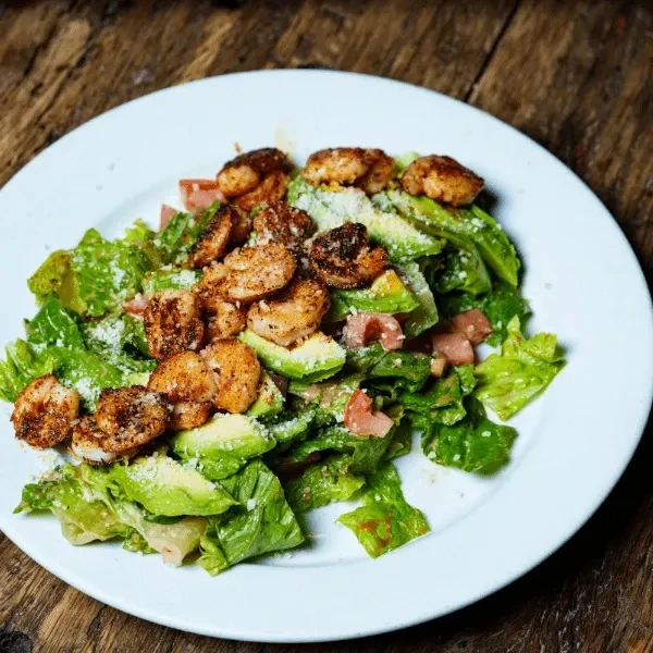 Grilled shrimp salad with avocado, tomatoes, lettuce, and Parmesan cheese.