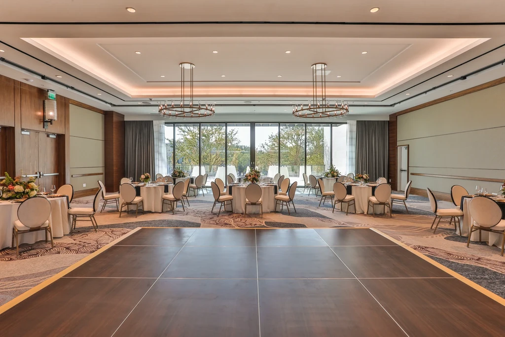 Empty, elegant banquet hall with dance floor, tables, and scenic window view.