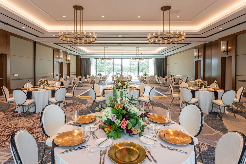 Spacious event hall, elegantly set with tables, flowers, and chandeliers.